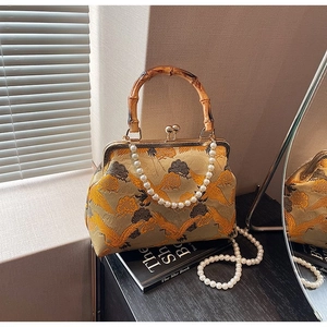 Detailed embroidery of crane pattern on handbag with bamboo handle and pearl strap