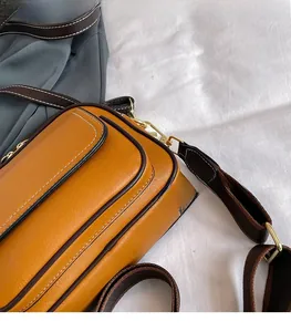 Detail der gelben Tasche mit Litschi-Lederstruktur, Kontrastkanten und breitem Schultergurt