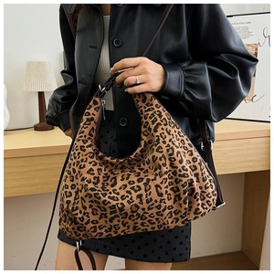 Close-up of leopard print hobo bag showing textured fabric and brown leather handle strap