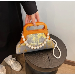 Détail du sac en tissu gris avec texture dorée, poignée en bois et breloques perles