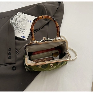 Detail view of green jacquard frame bag with bamboo handle and pearl chain strap