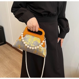 Détail d'un sac à main gris à feuilles d'or avec poignée en bois et charms en perles chics