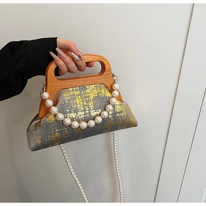 Détail du sac à main triangle gris avec poignée en bois et bandoulière en perles
