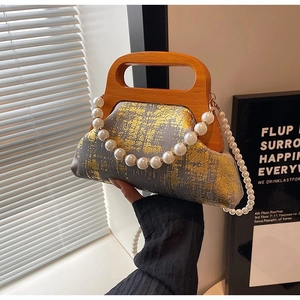 Détail du sac à main en tissu gris à motifs dorés, poignée en bois et bandoulière perle