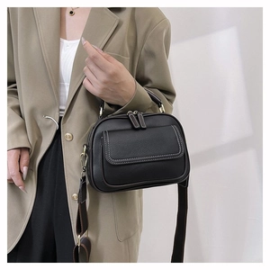 Nahaufnahme der schwarzen Lederhandtasche mit weißen Kontrastnähten und breitem Gurt