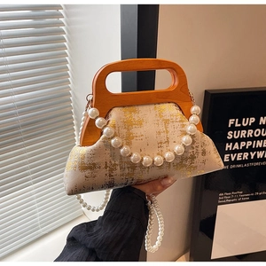 Détail d'un sac crème rétro avec texture dorée et bandoulière élégante en perles