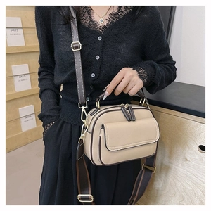 Detailaufnahme der beigen Ledertasche mit zwei Riemen und eleganten Goldbeschlägen