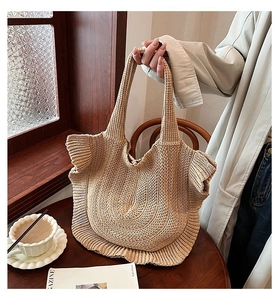 Detail of knit crochet tote bag with ruffle trim on wooden table with coffee cup
