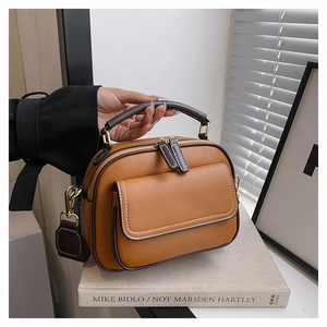 Details einer braunen Kunstledertasche mit Lychee-Struktur und goldfarbenen Reißverschlüssen