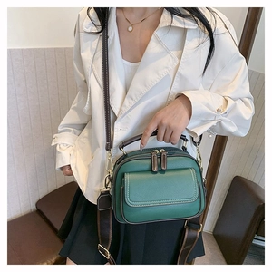 Detailansicht einer grünen Vintage-Ledertasche mit weißen Nähten und Umhängegurt