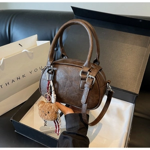 Brown Boston handbag detail with plush bear charm in a stylish gift box setup