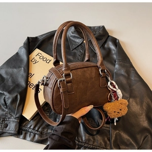 Detail of vintage brown cylinder Boston bag with plush bear charm and sturdy handles