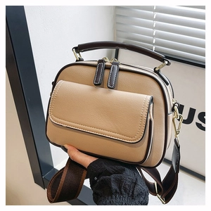 Detailansicht der beigen Lederstruktur und des braunen Griffs der Handtasche aus Leder