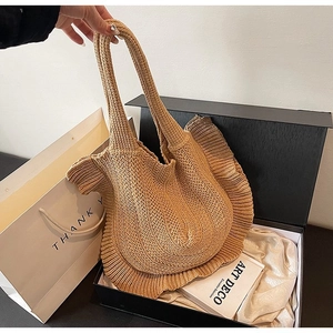 Detail of warm khaki knitted tote bag with ruffle trim on silk lining and gift box