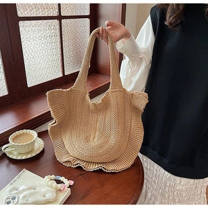Detail of beige knit tote bag with elegant ruffle trim on a cafe window background