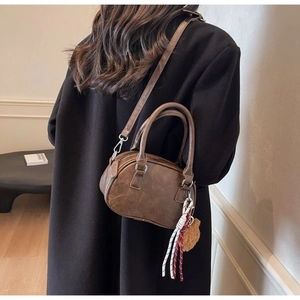 Detail of vintage brown faux leather Boston bag with teddy bear charm and woven strap