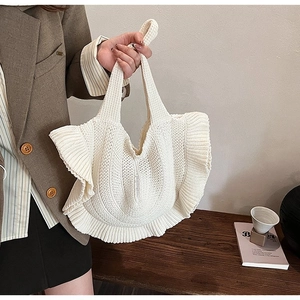 Close-up of a warm white knitted handbag featuring elegant side ruffle wave details