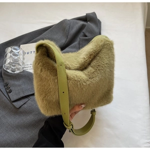 Detailed view of green plush faux fur texture and adjustable leather strap of the shoulder bag