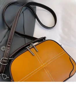 Detail of yellow leather crossbody bag with brown trim and contrast stitching accents