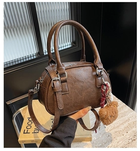 Detailed view of caramel brown crossbody bag with vintage texture and bear charm