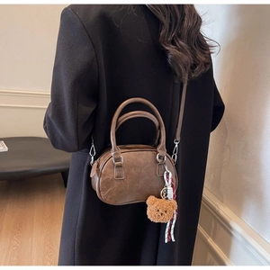 Close-up of retro brown Boston bag with plush bear charm and silver hardware detail