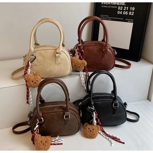 Mini bowling handbags in four colors with plush bear charms on marble steps
