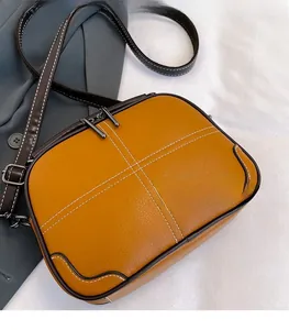 Detail of ginger yellow pebble leather crossbody bag with dual zippers and cross stitching
