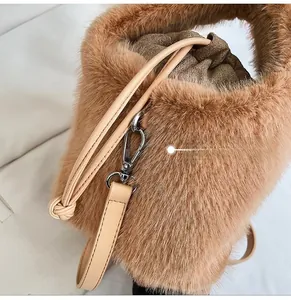 Detail der weichen braunen Plüsch-Beuteltasche mit silbernen Clips und beigen Lederriemen