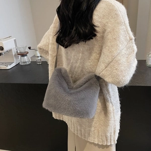 Detailed view of gray faux fur shoulder bag with long plush texture worn by a model