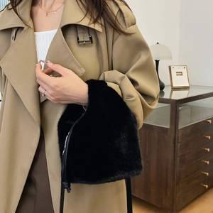 Detail der schwarzen Kunstfell-Beuteltasche mit Kordelzug zu einem beigen Trenchcoat
