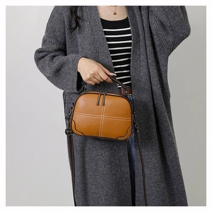 Detail of caramel brown crossbody bag with lychee texture and white cross stitching