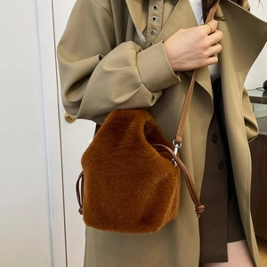 Detail der Plüsch-Beuteltasche in Karamell mit Kordelzug und Lederriemen am Modell