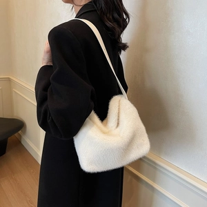 Detail of white faux fur crossbody bag shown with black wool coat for texture contrast
