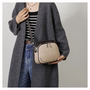 Retro beige crossbody bag with dark brown trim shown on model for size and style