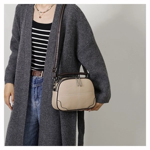 Detail of beige and brown leather crossbody bag styled with a gray cardigan
