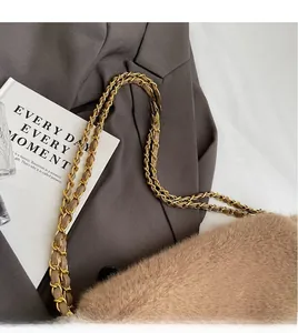 Detail of plush brown shoulder bag featuring woven gold metal and leather chain strap