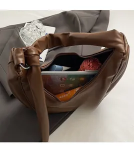 Spacious interior of brown matte leather dumpling bag holding a tablet and umbrella
