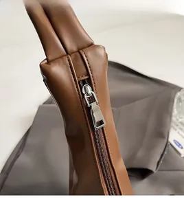 Detail of silver metal zipper and precise stitching on brown lychee leather bag