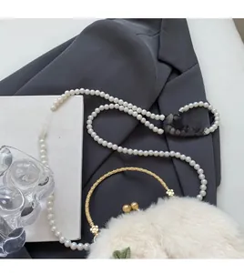 Detail of off-white faux fur shoulder bag with pearl strap and gold metal handle