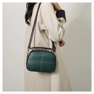 Detail of dark green leather shoulder bag with white cross stitching and silver hardware