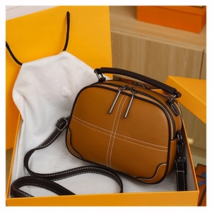 Macro detail of brown leather bag with white stitching and zipper in an orange gift box