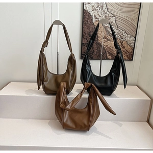 Detail of stitched dumpling bags in dark brown, black and tan with knotted handle designs