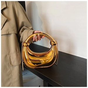 Détail d'un sac de soirée doré en forme de croissant avec poignée ronde et bandoulière