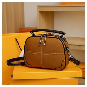 Detailed view of brown lychee grain leather crossbody bag with white contrast stitching