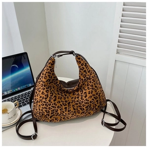 Leopard print tote bag with brown leather straps on a white table with laptop