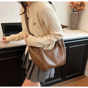 Detailed view of dark brown leather hobo bag with stitched edges in an office setting