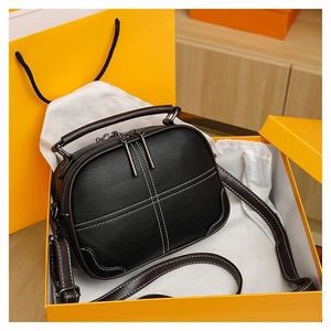 Detail of black pebbled leather crossbody bag with stitching and luxury orange packaging