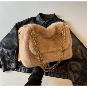 Detail of light khaki faux fur shoulder bag with gold chain strap on black leather jacket