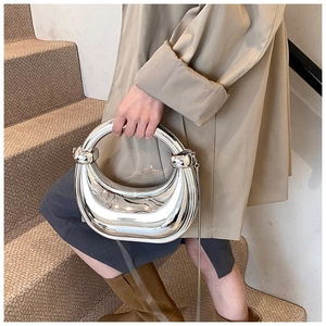 Pochette argentée en demi-lune avec poignée anneau portée dans un cadre chic de rue
