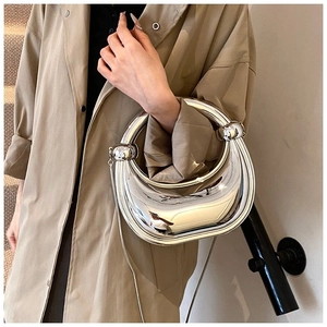 Détail d'un sac à main miroir argenté avec poignée ronde et nœuds sphériques modernes